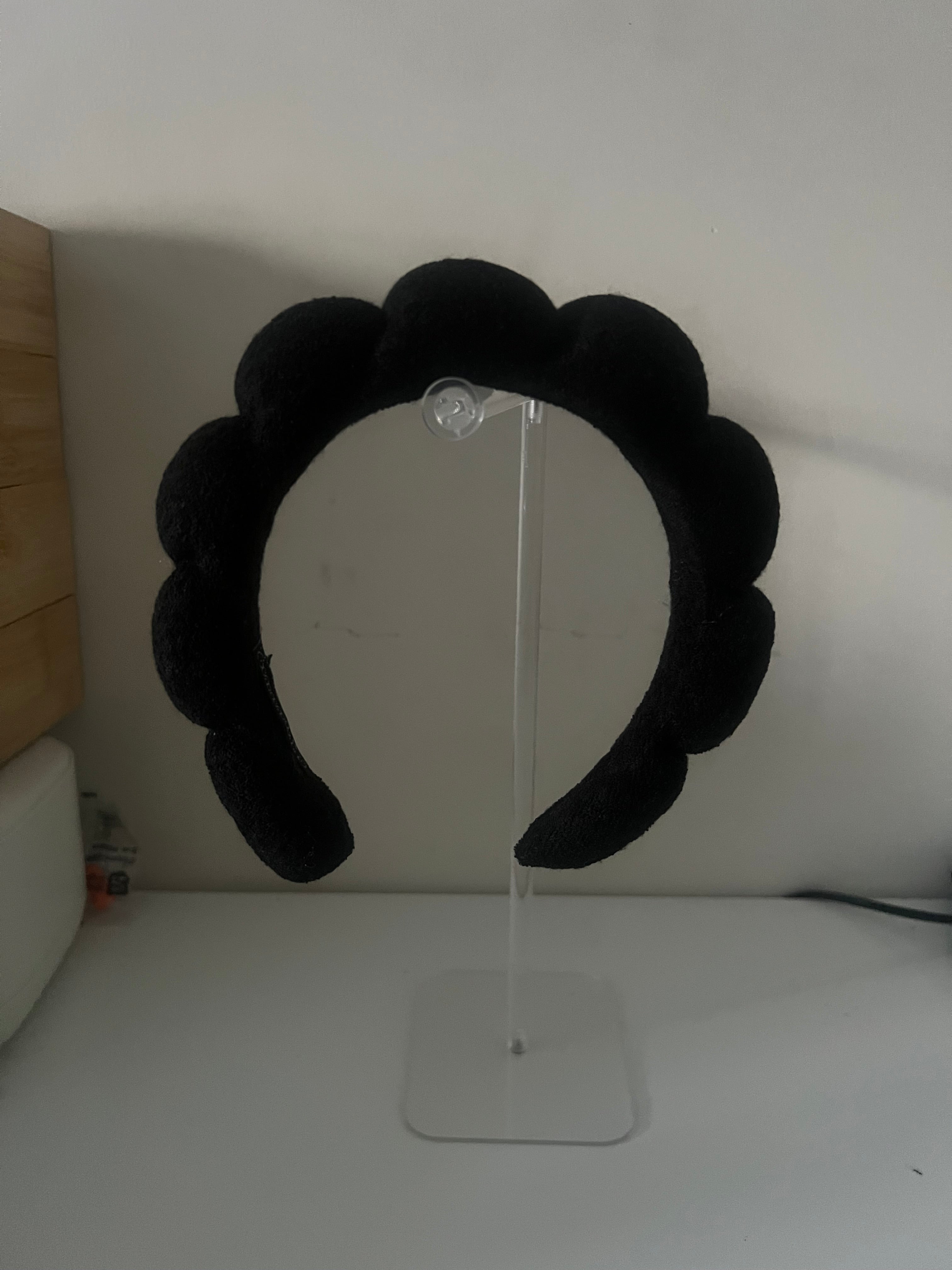 Black bubble headband displayed on a clear acrylic headband stand