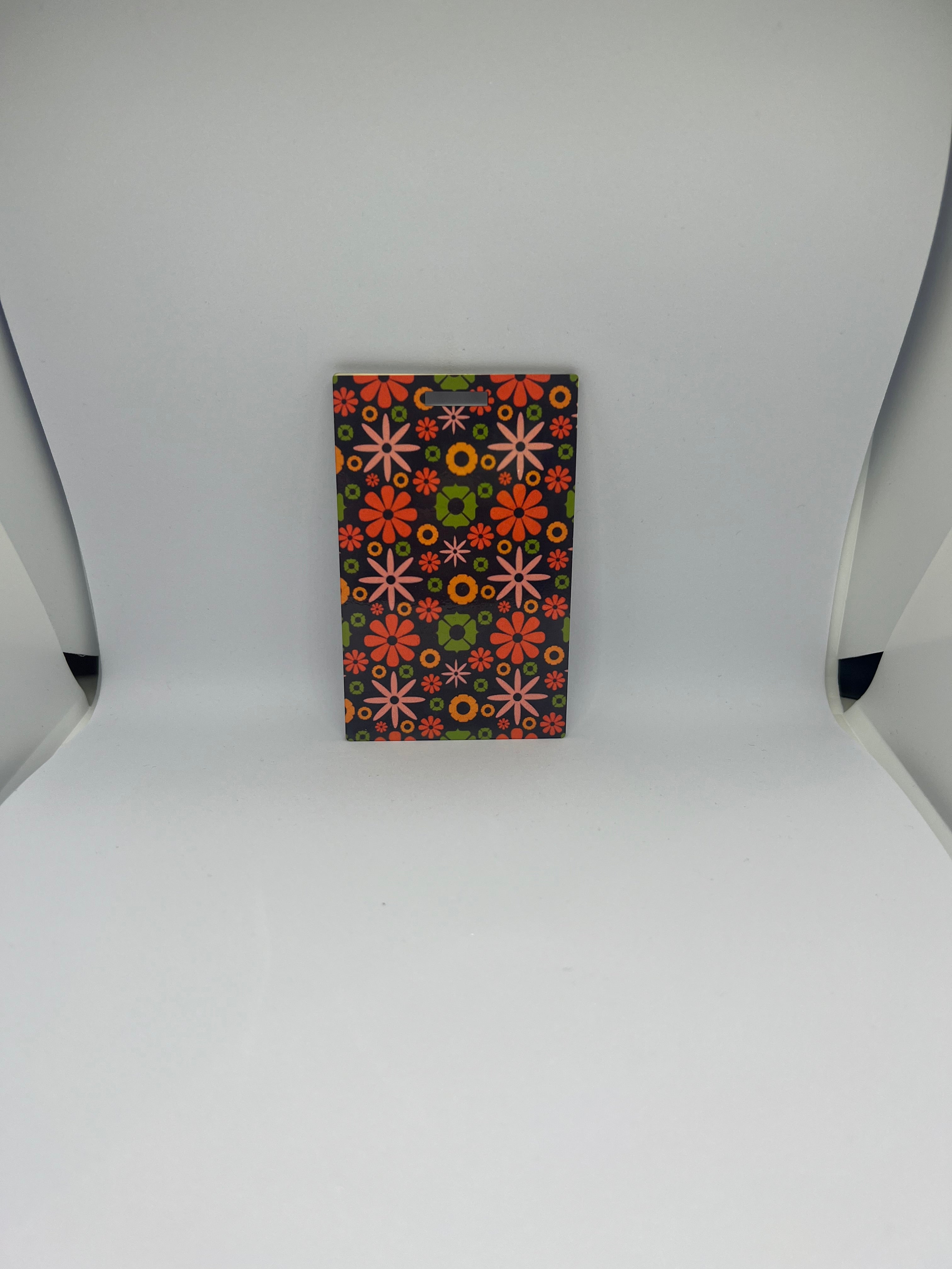 Retro floral luggage tag with colourful daisy pattern in pink orange green and yellow on dark background
