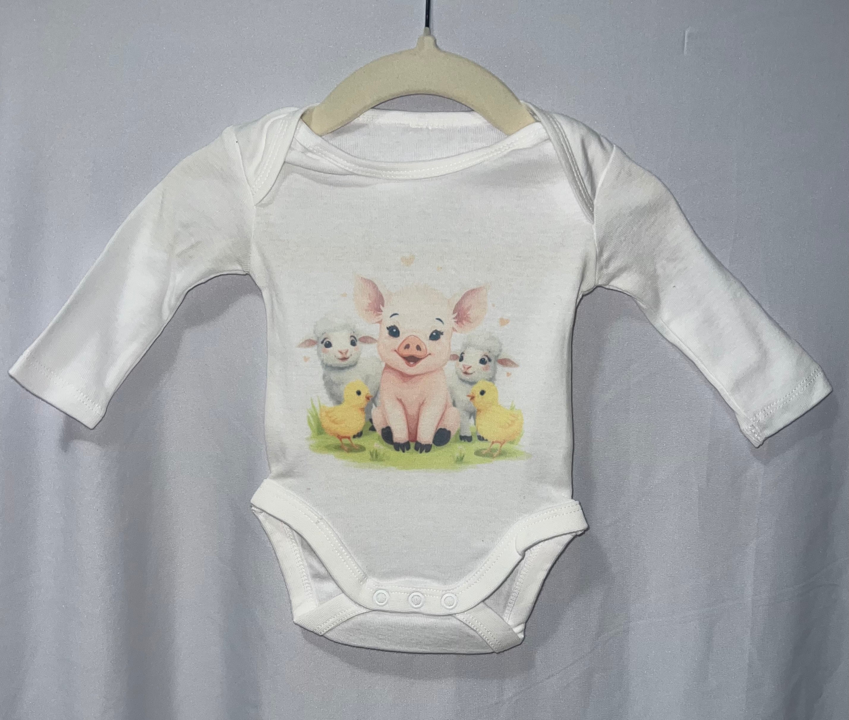 White long sleeve baby onesie with watercolour piglet lambs and chicks farm animals print on hanger