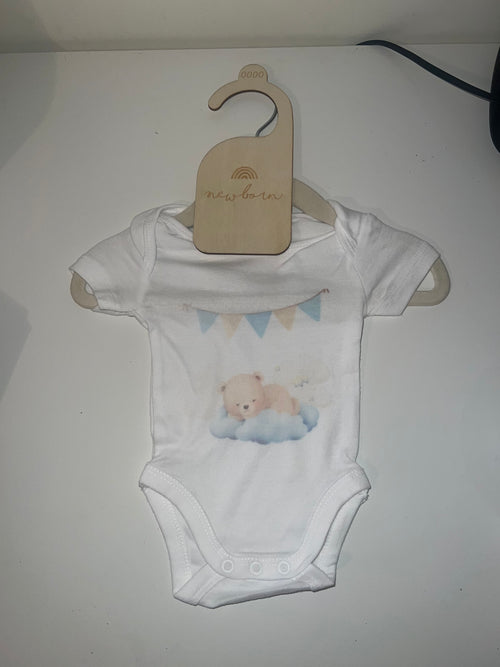 White short sleeve baby onesie with watercolour sleepy teddy bear on cloud and blue bunting print on newborn hanger