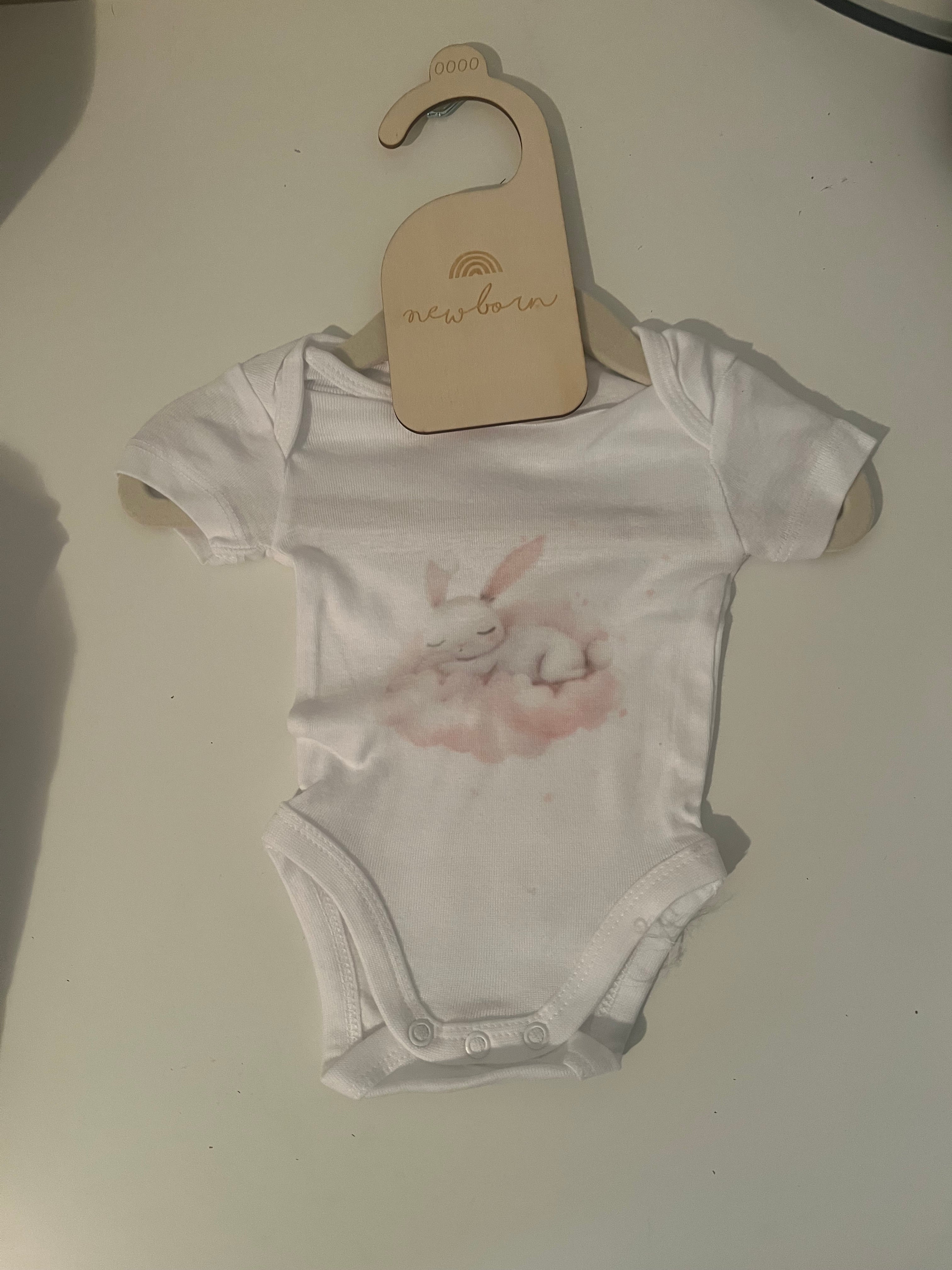 White short sleeve baby onesie with watercolour sleepy bunny in blush and white tones on newborn hanger