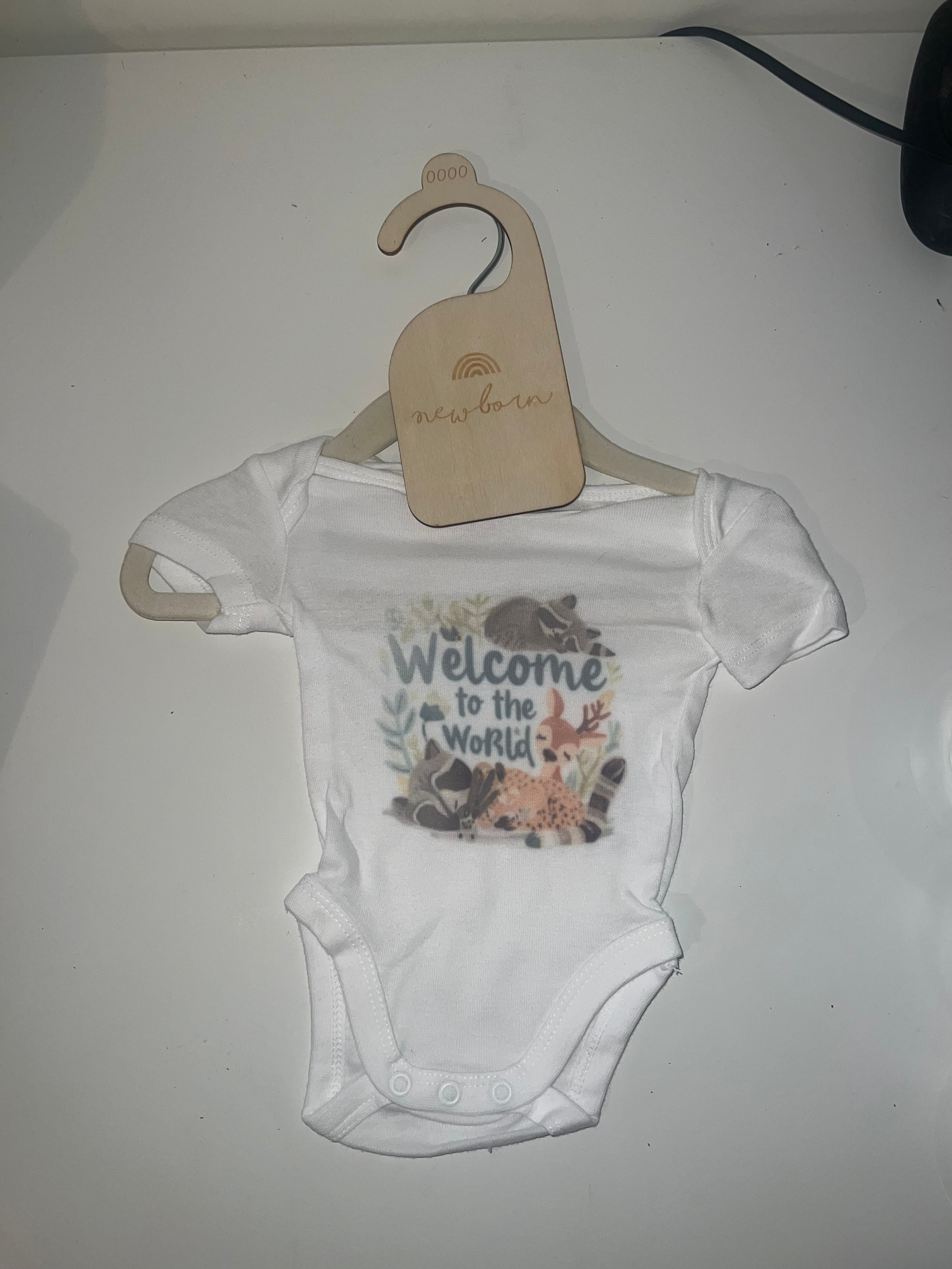 White short sleeve baby onesie with woodland watercolour Welcome to the World print with fawn and botanicals on newborn hanger