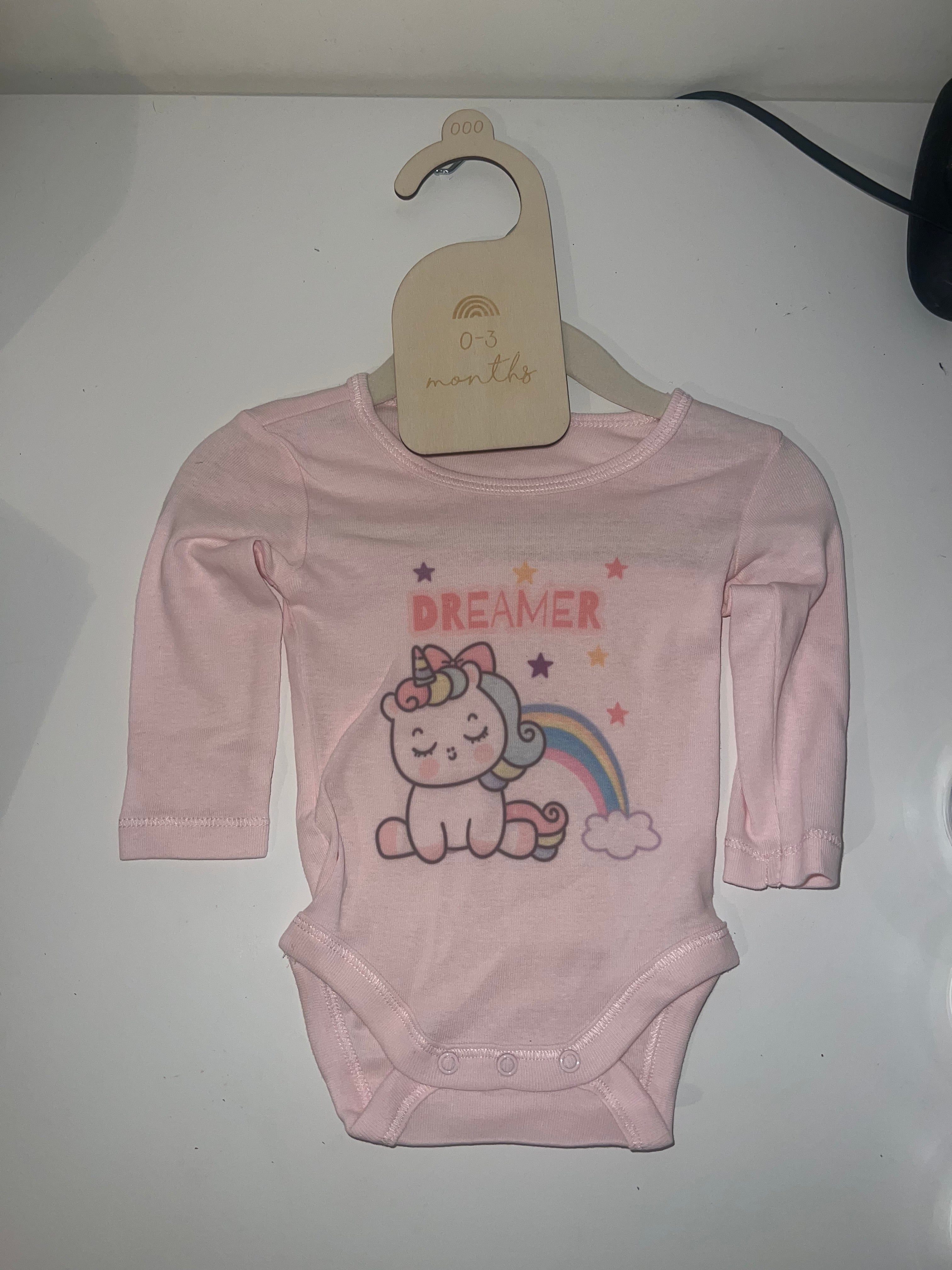 Blush pink long sleeve baby onesie with unicorn rainbow and Dreamer print on 0-3 months hanger