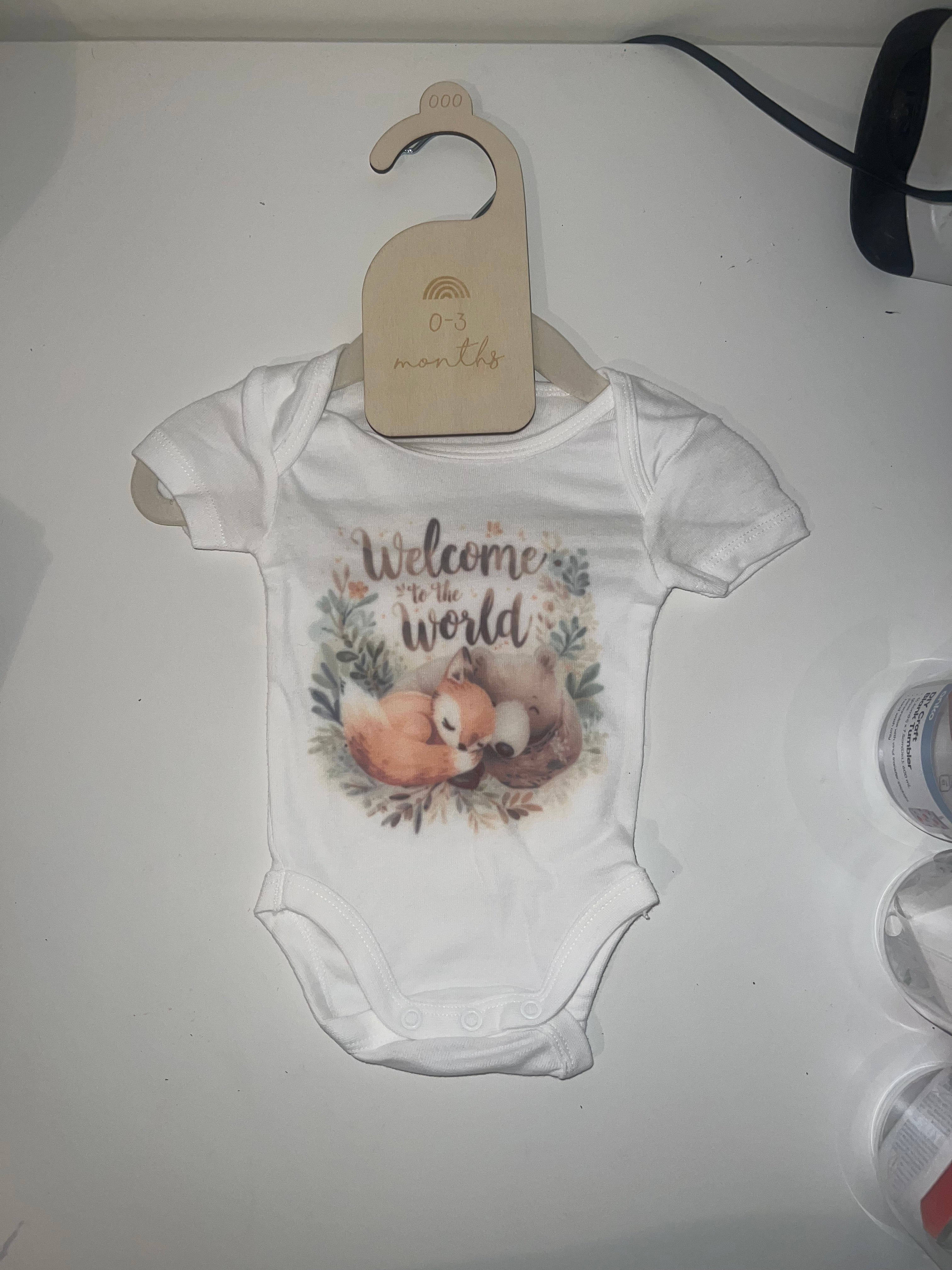 White short sleeve baby onesie with watercolour sleeping fox and botanical leaves Welcome to the World print on 0-3 months hanger