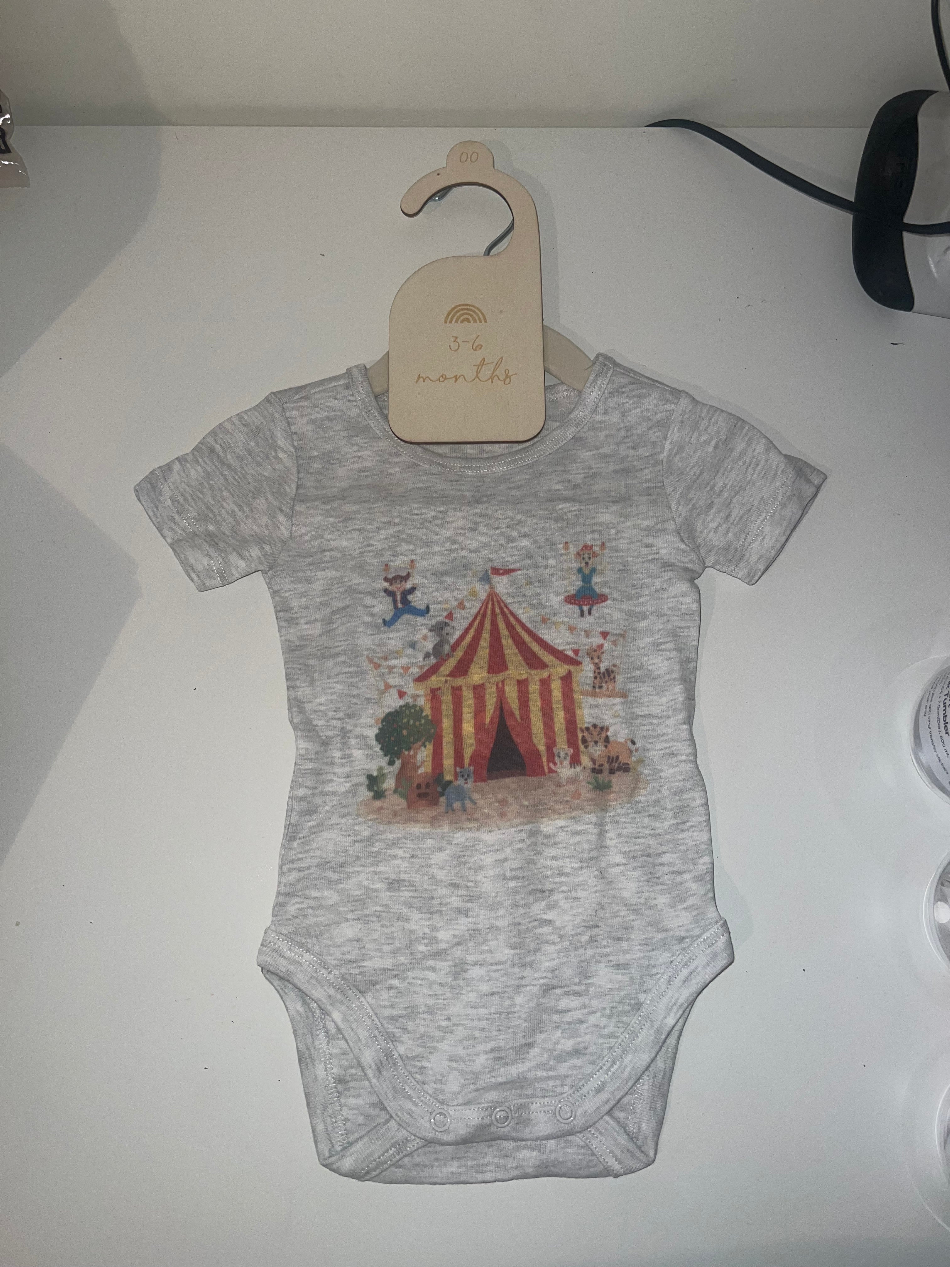 Grey marle short sleeve baby onesie with vintage circus tent acrobats and animals print on 3-6 months hanger