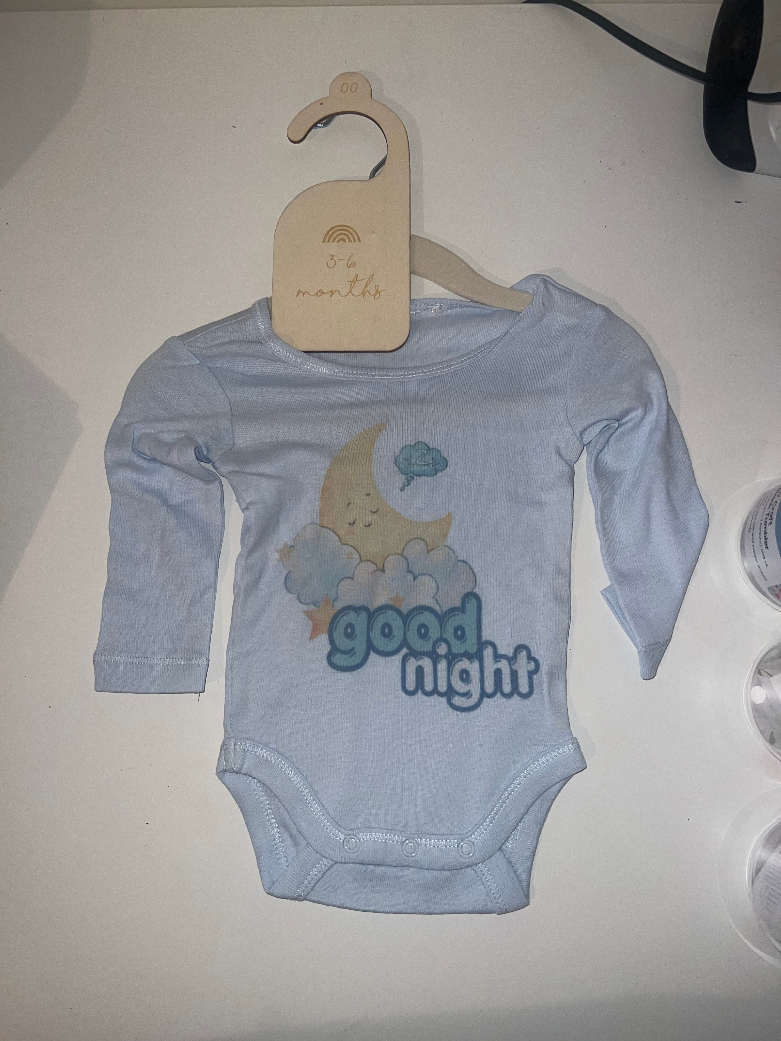 Sky blue long sleeve baby onesie with sleepy moon on clouds and Good Night print on 3-6 months hanger