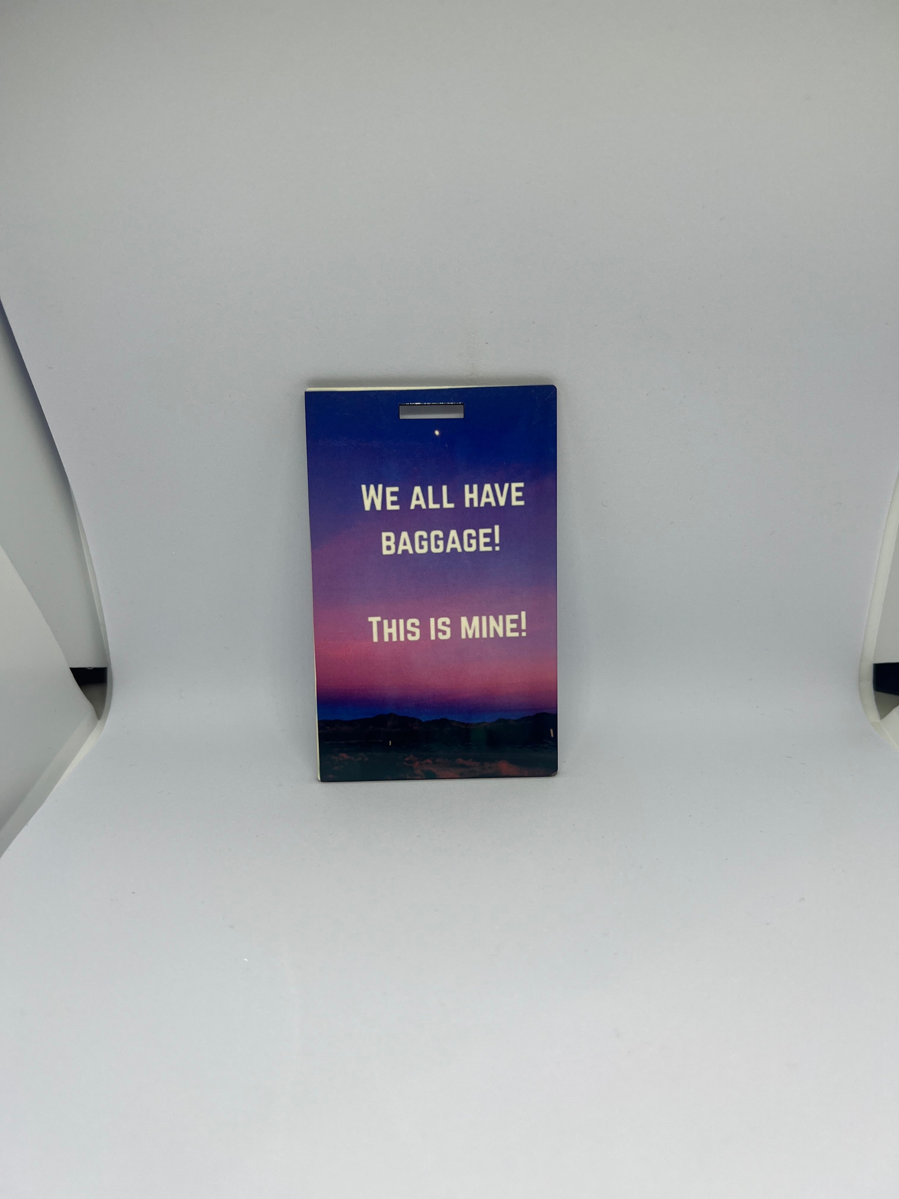 We All Have Baggage This Is Mine luggage tag with gold text on purple pink sunset sky background