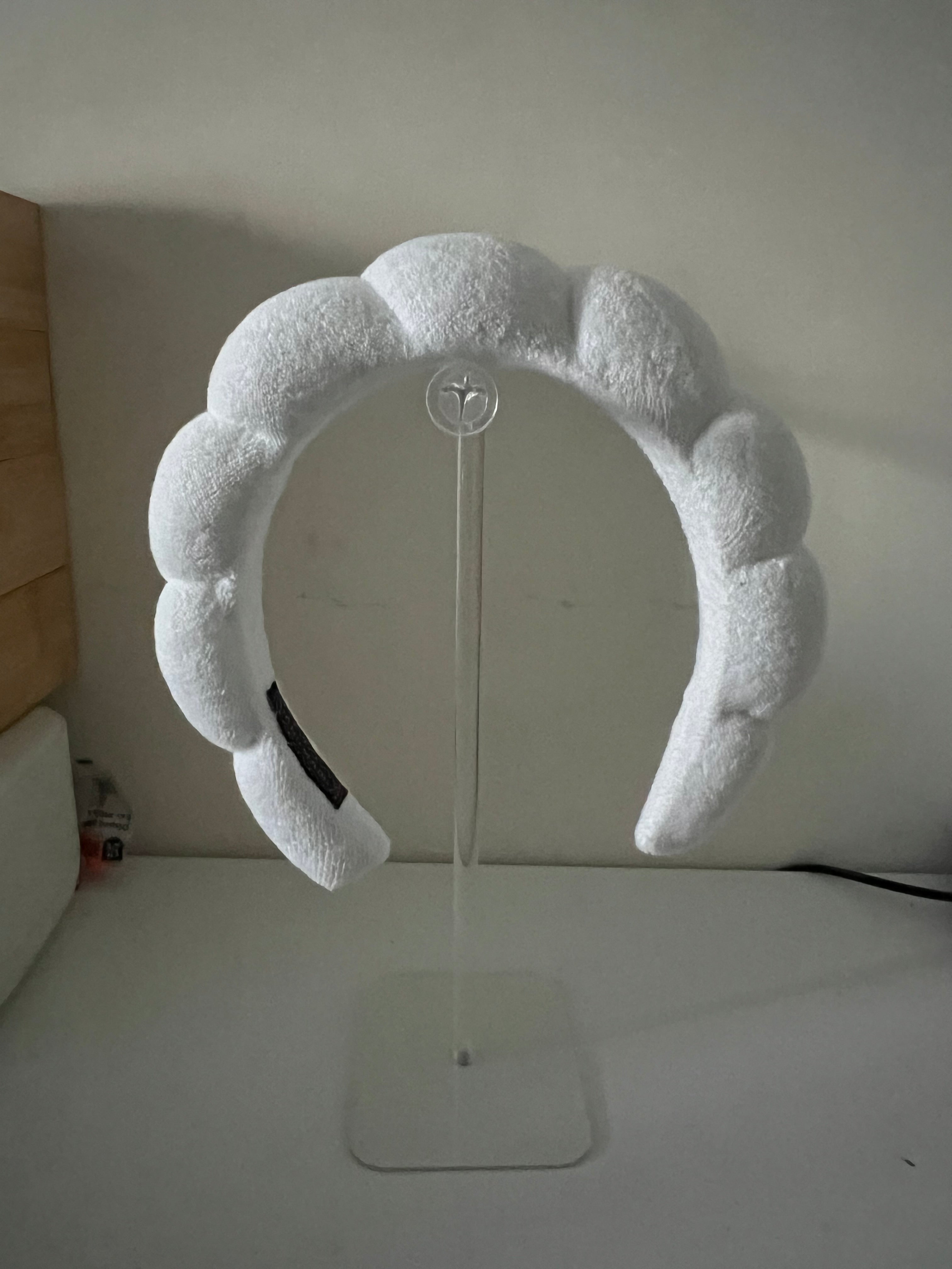 White terry-cloth bubble headband displayed on a clear acrylic headband stand
