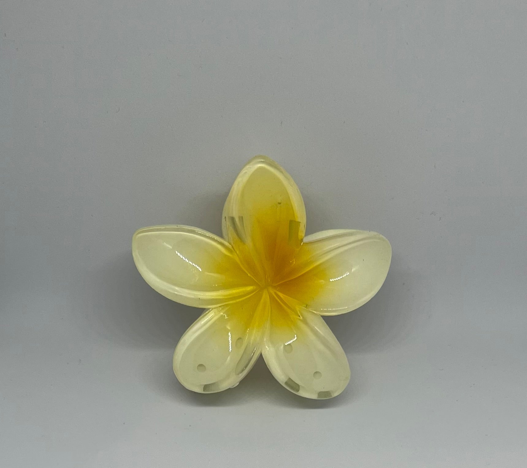 Yellow frangipani flower hair claw clip with translucent cream-yellow petals and golden amber centre